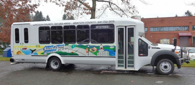 Sideview of a Coast to Valley Express bus. Artwork of the Benton County Courthouse and whales is on the side. 