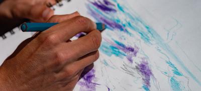 hands of an artist drawing a picture of the ocean waves