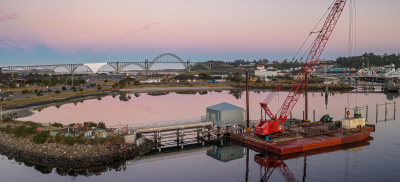 The Hatfield Marine Science Center at sunset with the Yaquina Bay Bridge in the background and the estuary in the foreground.