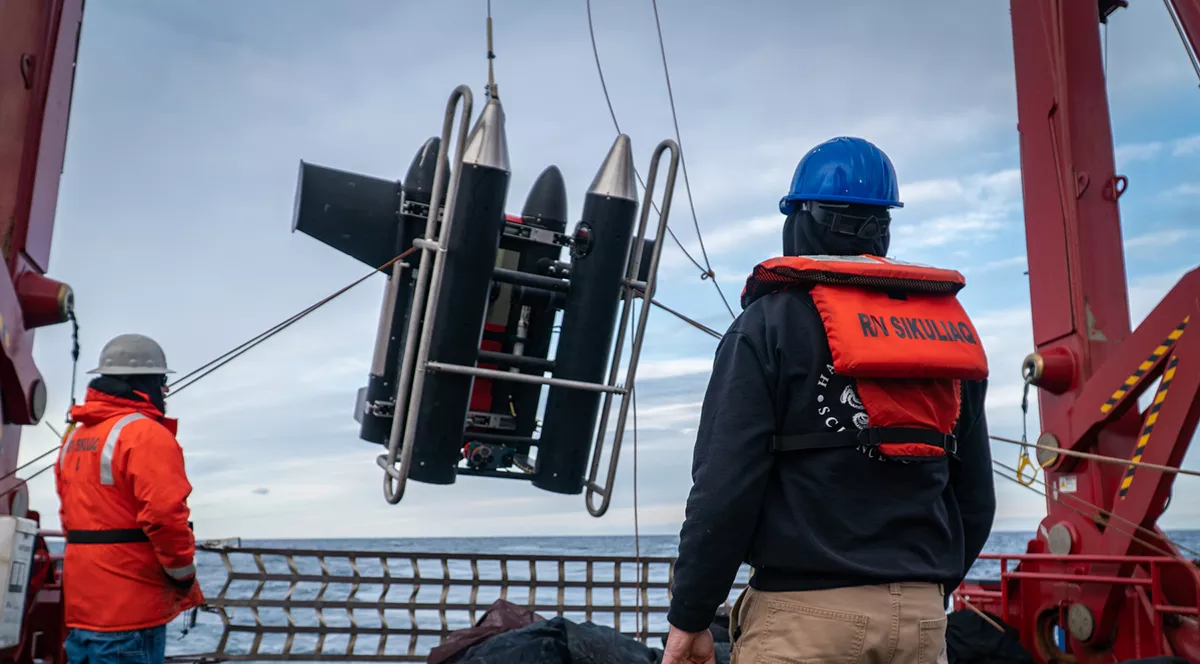 motorized deep water sampling equipment being lowered into the ocean off a boat