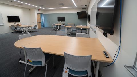 Classroom and meeting space at the Gladys Valley Marine Studies Building. Tables are grouped around the rooom next to TV monitors that hang from the walls.