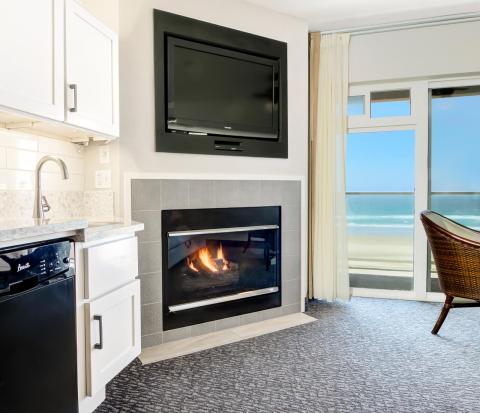 A hotel room with a fireplace, mini fridge and kitchenette