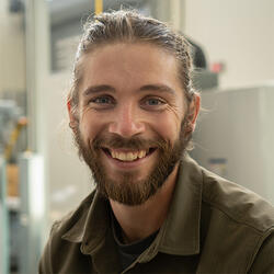 A man with a brown beard and long hair pulled back into a ponytail.