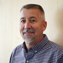 A man with a graying gotee and short salt and pepper hair. 