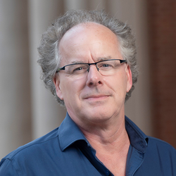 A man with gray receeding hair wearing glasses.