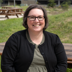 A woman with chin-length brown hair and dark framed glasses.