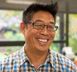 A man with short black hair and glasses.
