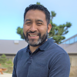 A man with short dark hair and a salt and pepper beard.