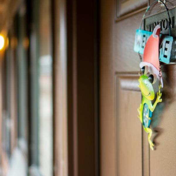 The entrance door to a Hatfield dorm room. A metal frog decoration hangs from the door.